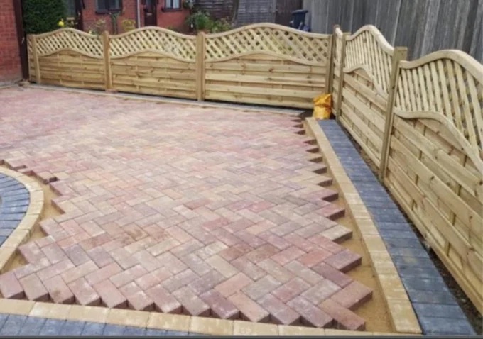 Block paving installation with dual charcoal and buff border alongside decorative timber fencing