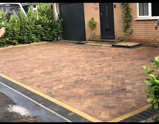 Herringbone block paving driveway with contrasting buff header course and charcoal border kerbs