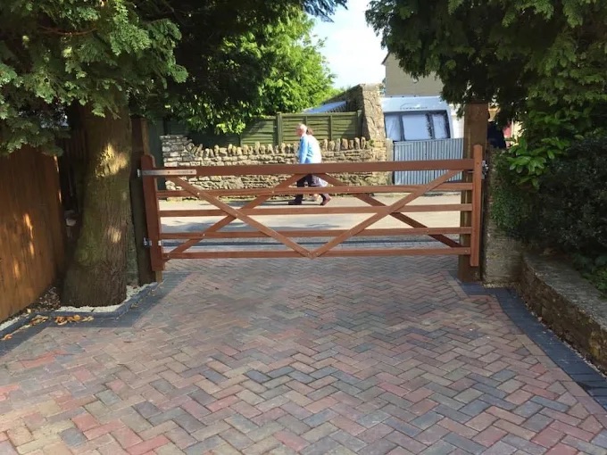 Herringbone block paved driveway approach with timber farm gate and dry stone boundary wall