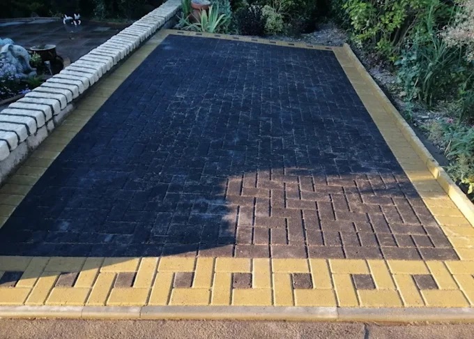 Charcoal block paved parking area with golden-yellow Greek key decorative border detailing