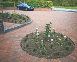 Red block-paved driveway forecourt with circular brick planter feature