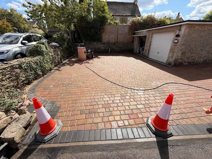 Tegula style rustic block paved driveway approach with curved charcoal kerb and stone boundary wall