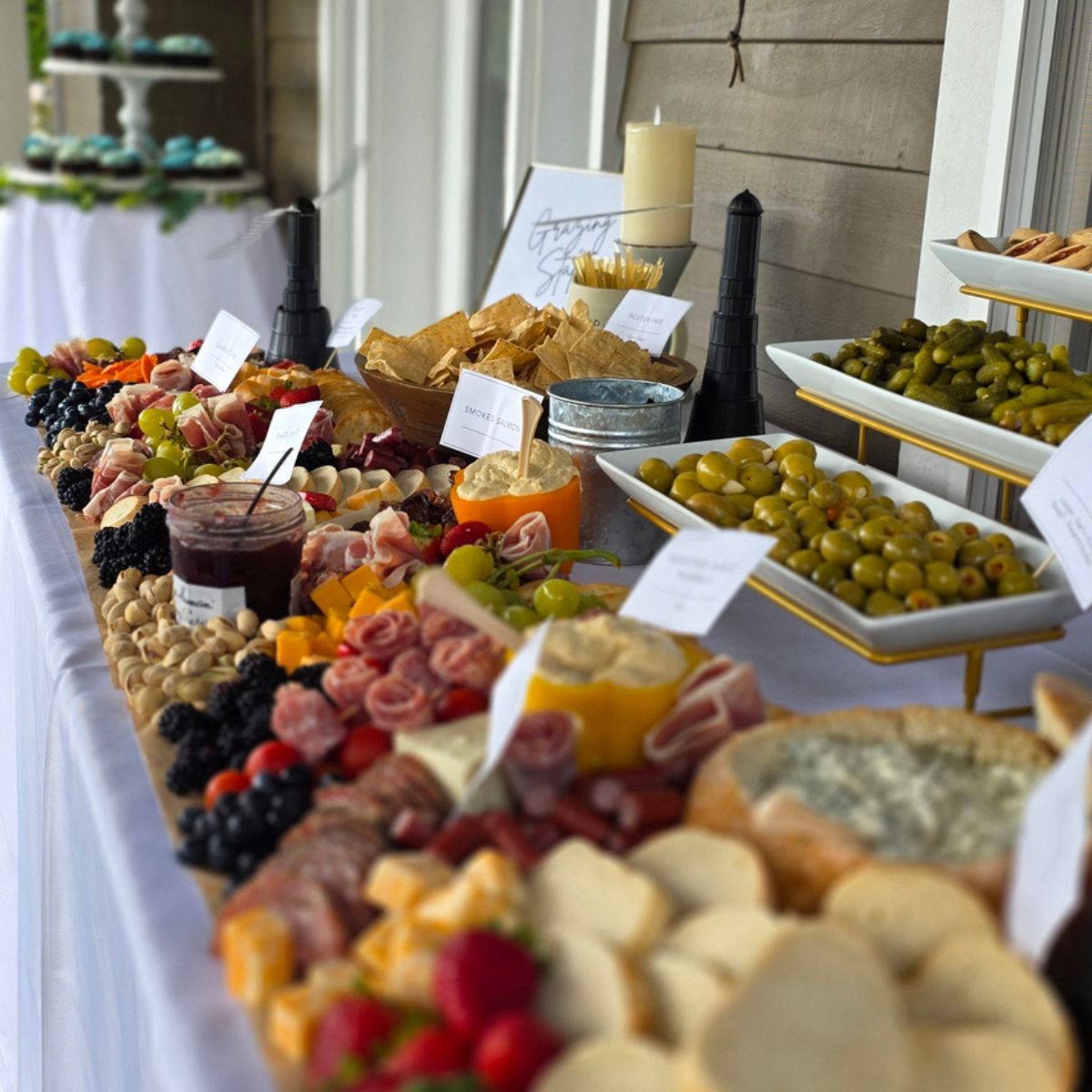 Luxury charcuterie grazing table catering display with artisan cheeses cured meats fresh fruits and custom labels for wedding reception