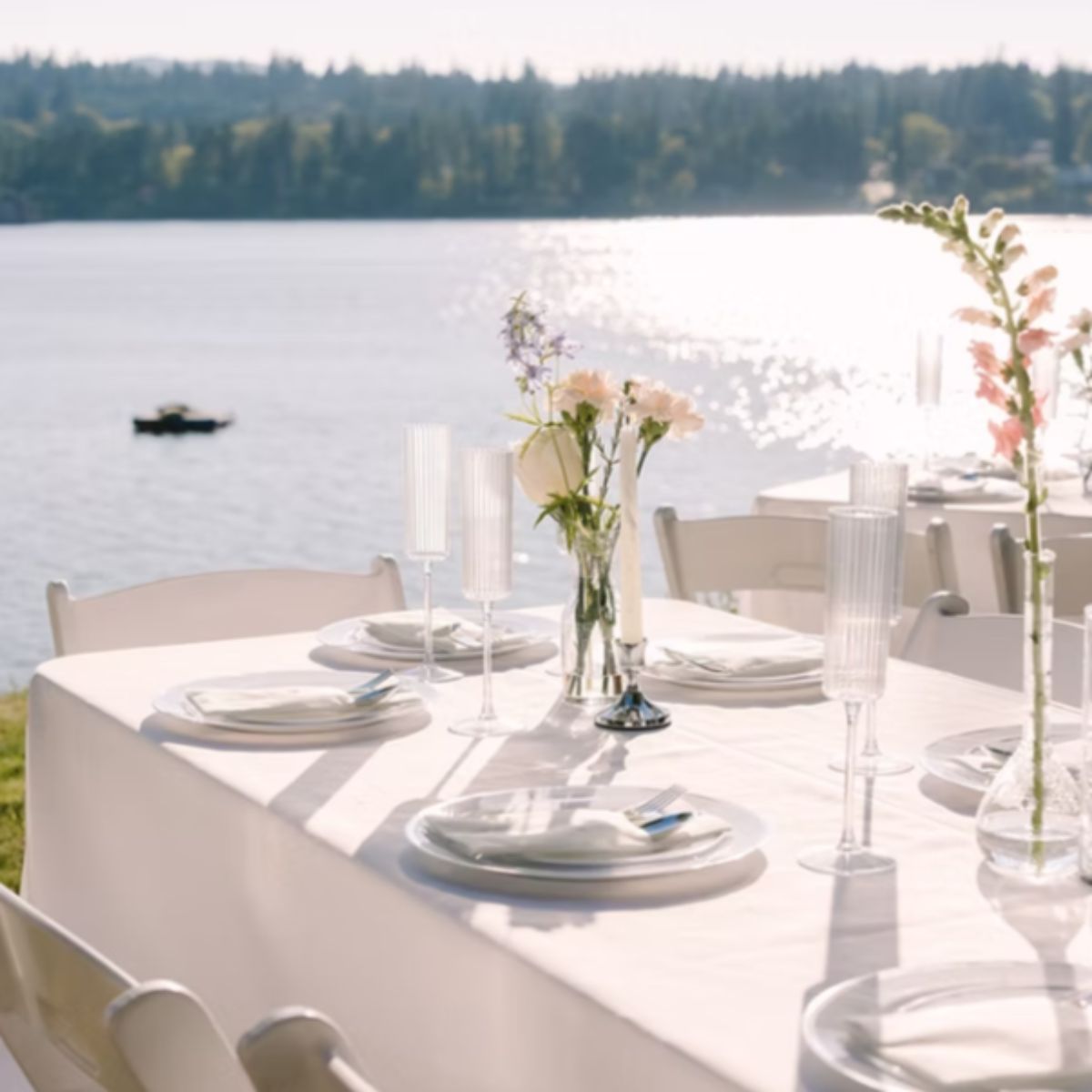 Elegant lakefront wedding reception table setting with fresh floral centerpieces and champagne flutes for outdoor event in Kitsap County