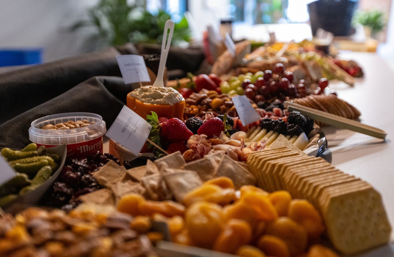 artisan gourmet grazing buffet station with labeled charcuterie, cured prosciutto, dips, crackers, and fresh fruit