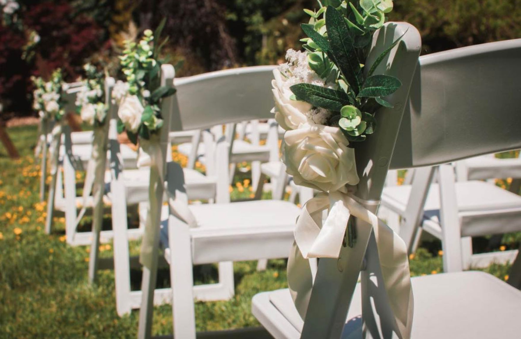 outdoor wedding ceremony aisle with floral chair decor coordinated by Honeybee Horticulture