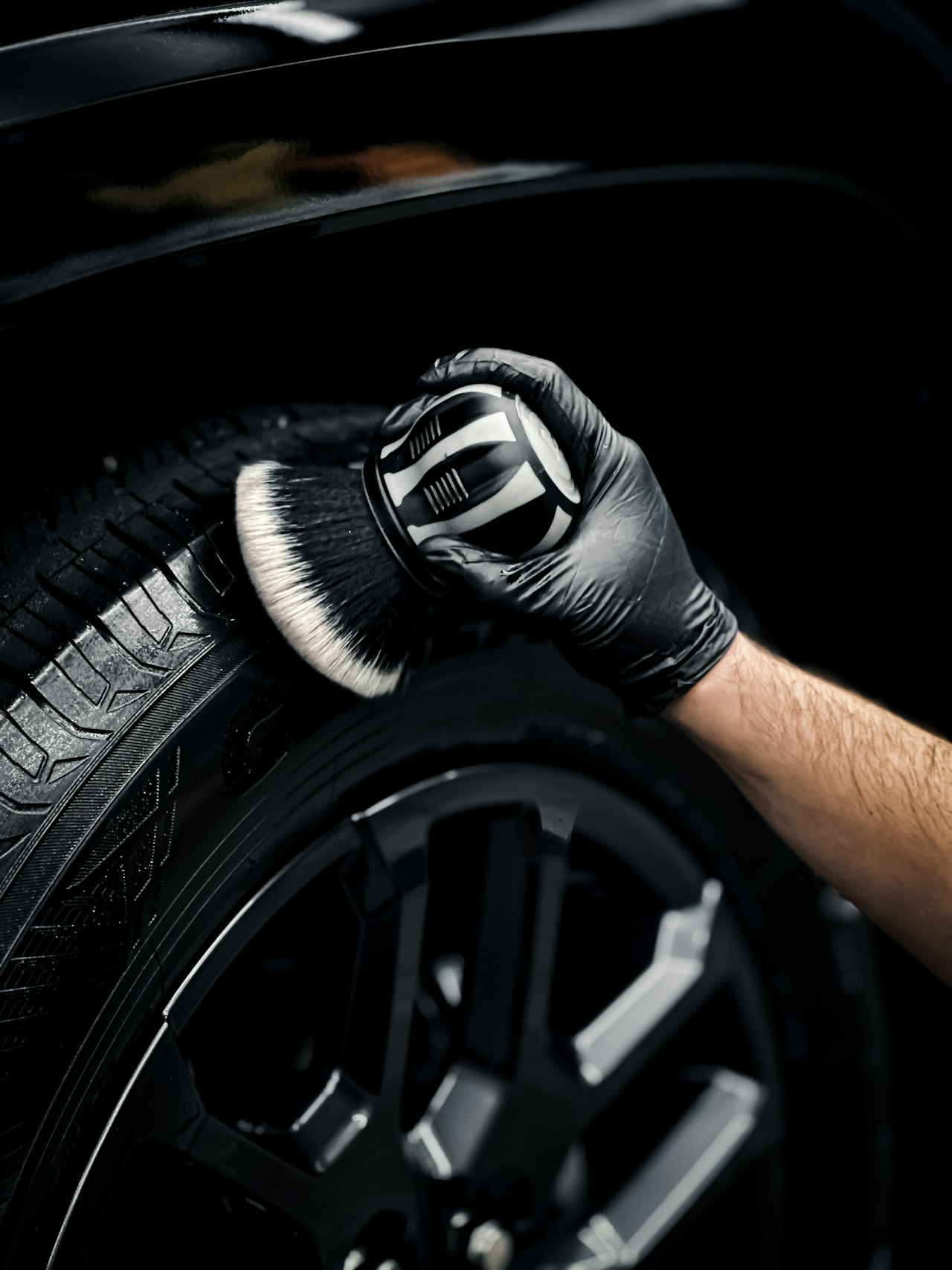 Detailer cleaning a vehicle wheel and tire with a detailing brush