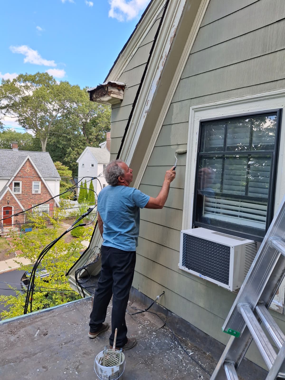 Professional painter applying paint to exterior siding on a house