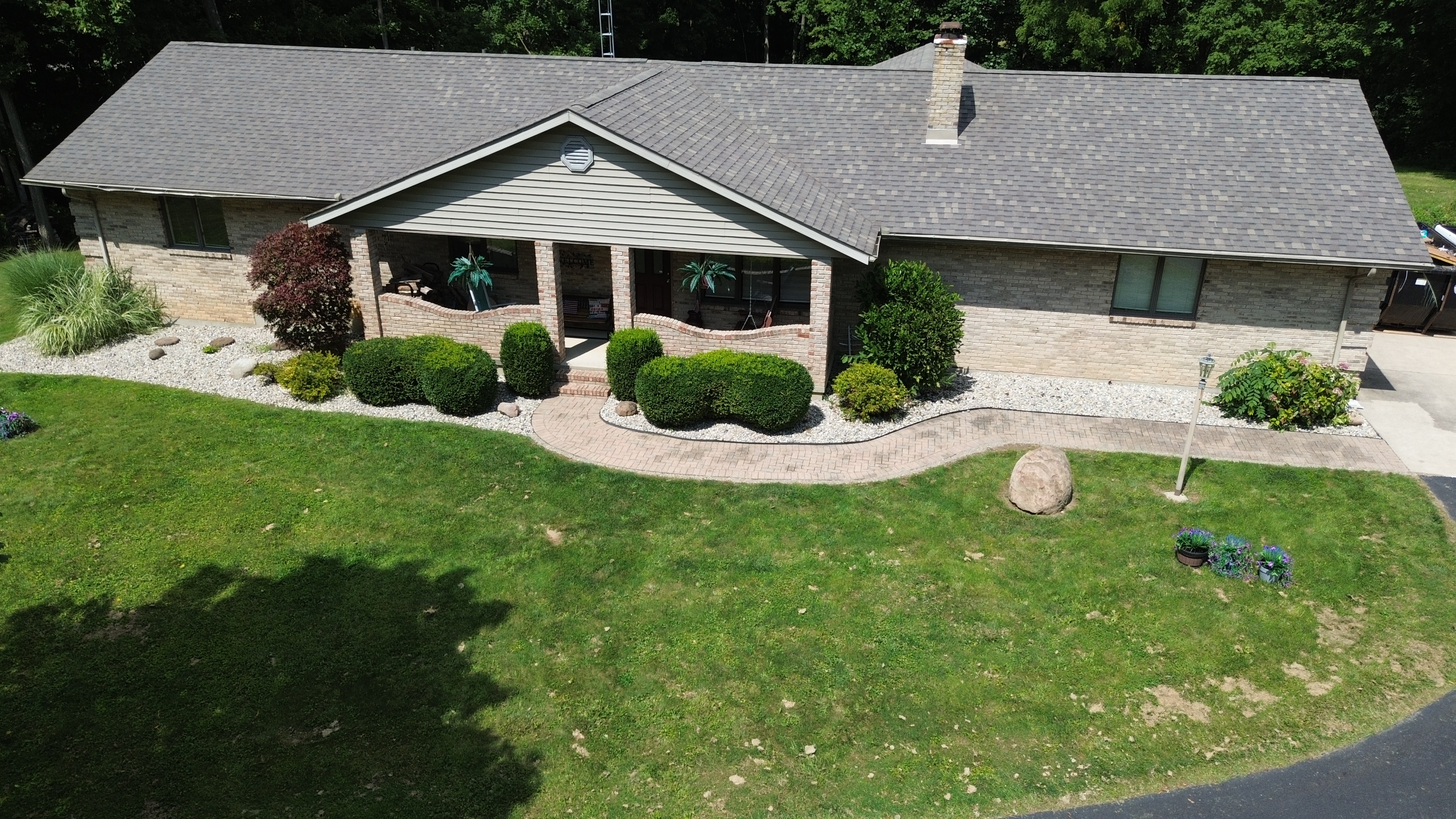 Aerial view of completed architectural shingle roof on brick ranch home