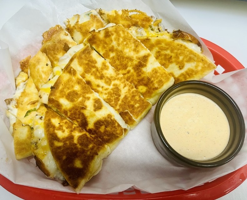 Wildhorse Bar & Grill Cheese Quesadilla grilled golden and sliced into wedges, served in a red lined basket with house dipping sauce