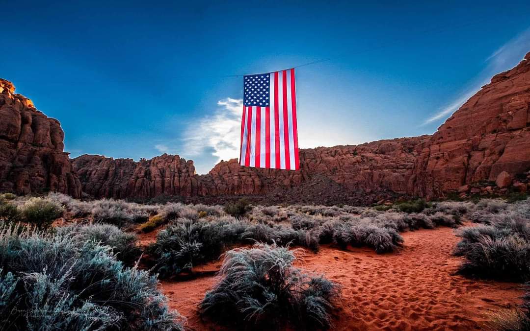 Giant 78x150 foot American flag suspended between the red rock cliffs of Snow Canyon State Park