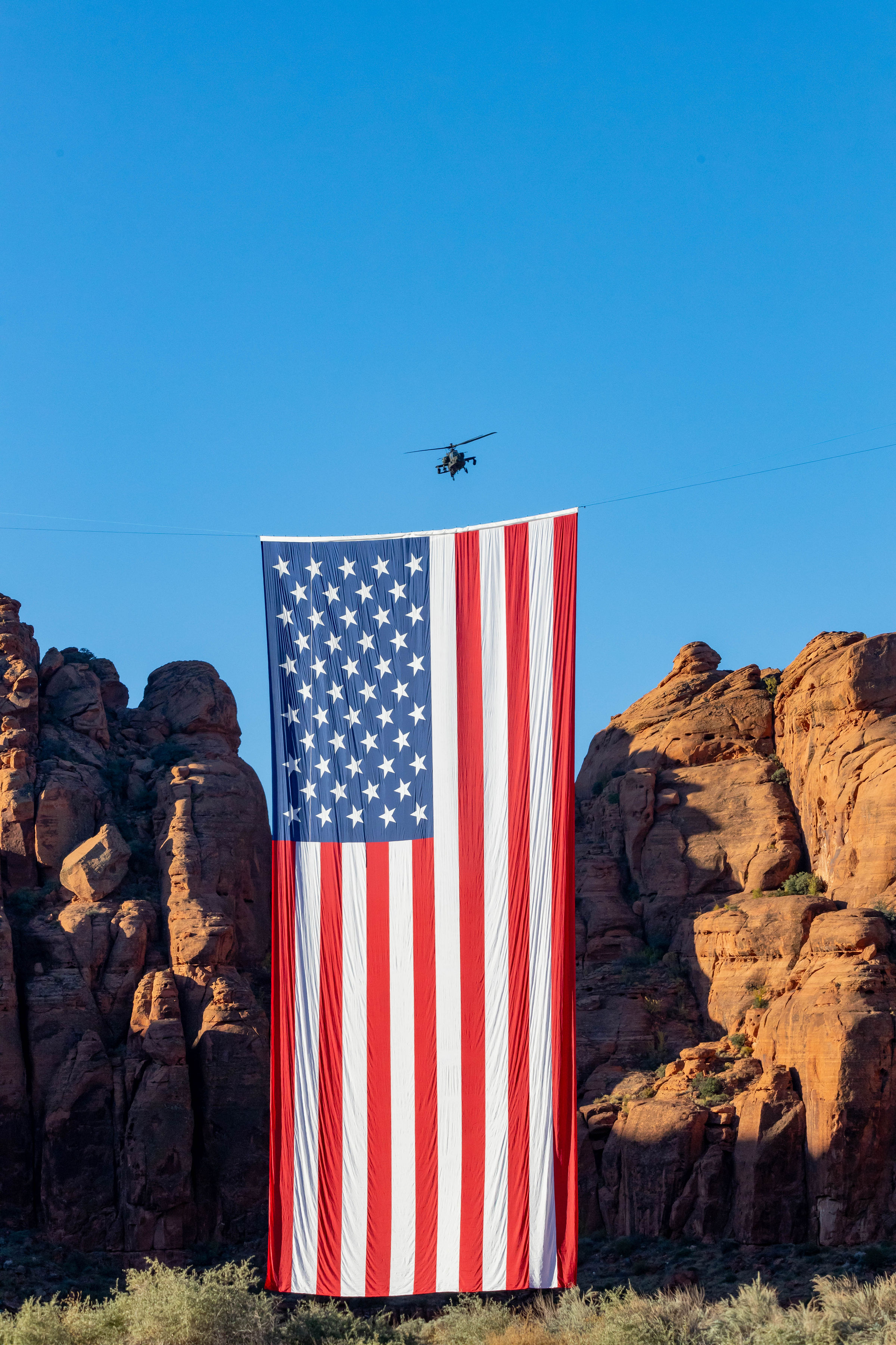 Giant 78-by-150-foot American flag suspended between the red cliffs of Snow Canyon State Park