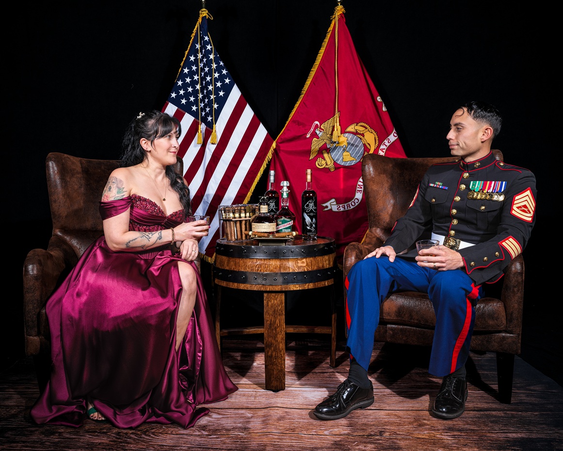 Marine Staff Sergeant and guest in formal evening gown seated in leather armchairs with American and Marine Corps flags at an authentic Elite360 event setup