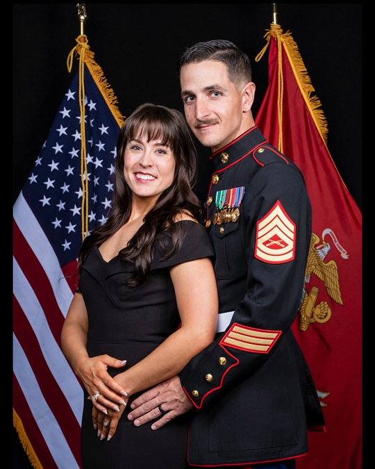 Marine First Sergeant and spouse posing in formal dress uniform with national and Marine Corps colors at an Elite360 event