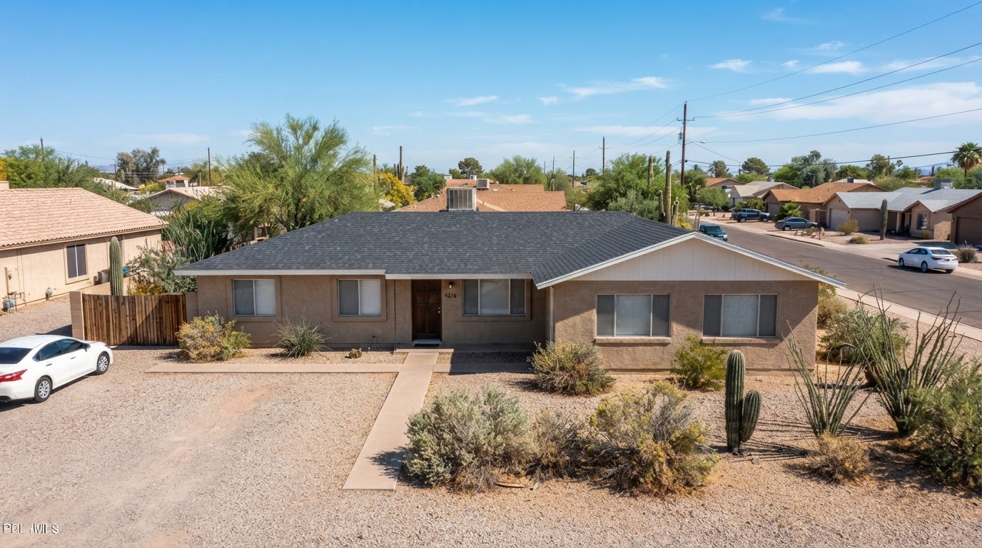 A larger modest single-story tan stucco home with a regular composite shingle roof in a regular Phoenix desert neighborhood, suited for shared sober living