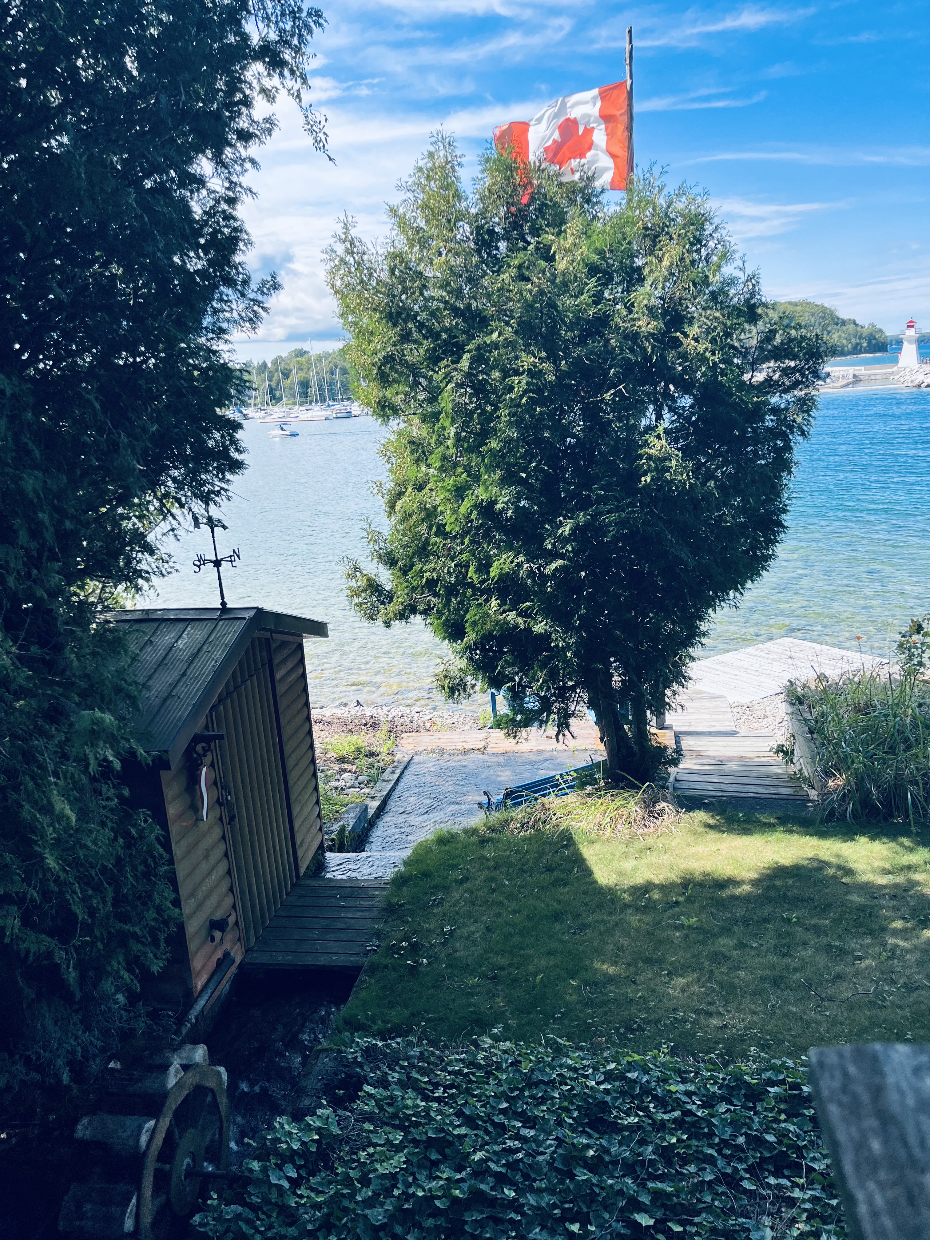 Private stream and waterwheel running down to the lodge dock and Georgian Bay with the Canadian flag