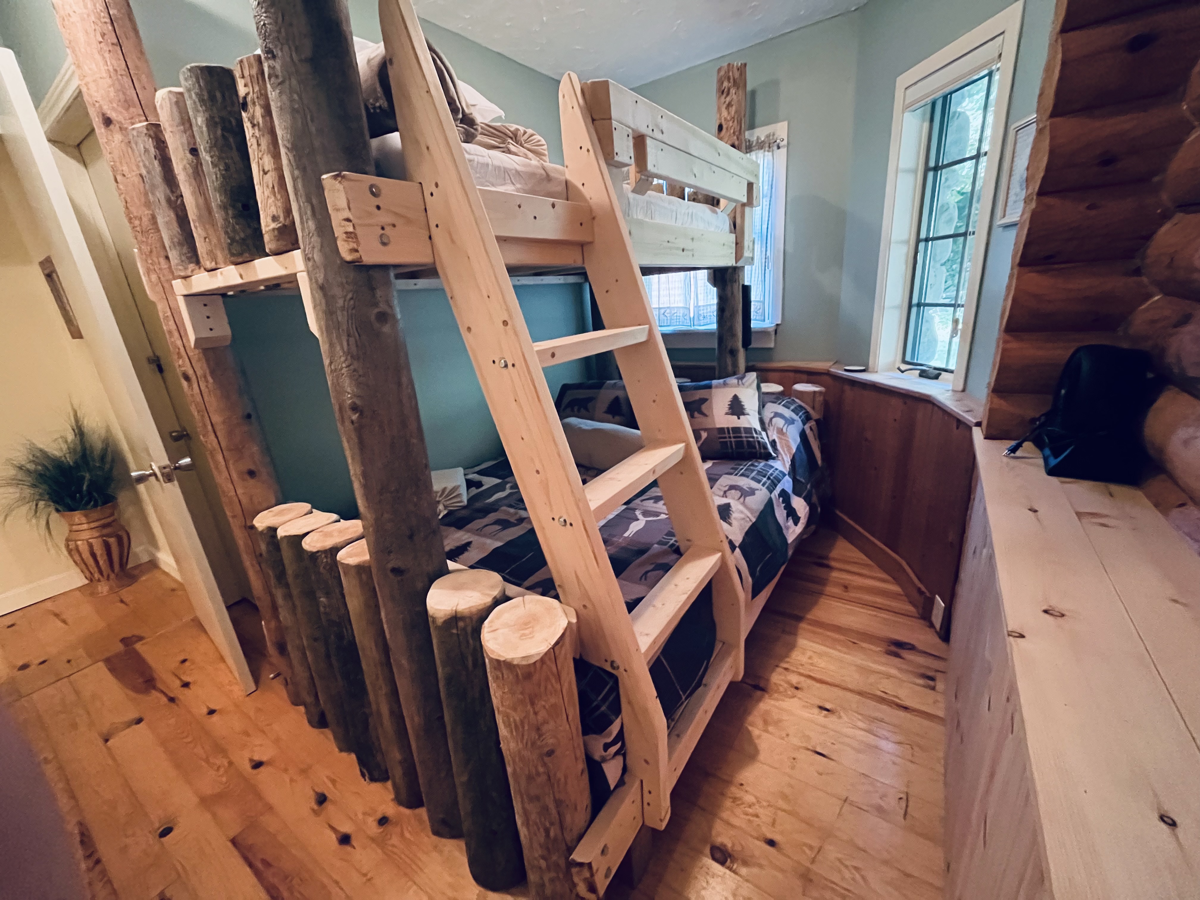 Handcrafted rustic timber bunk beds with wooden ladder and hardwood floors