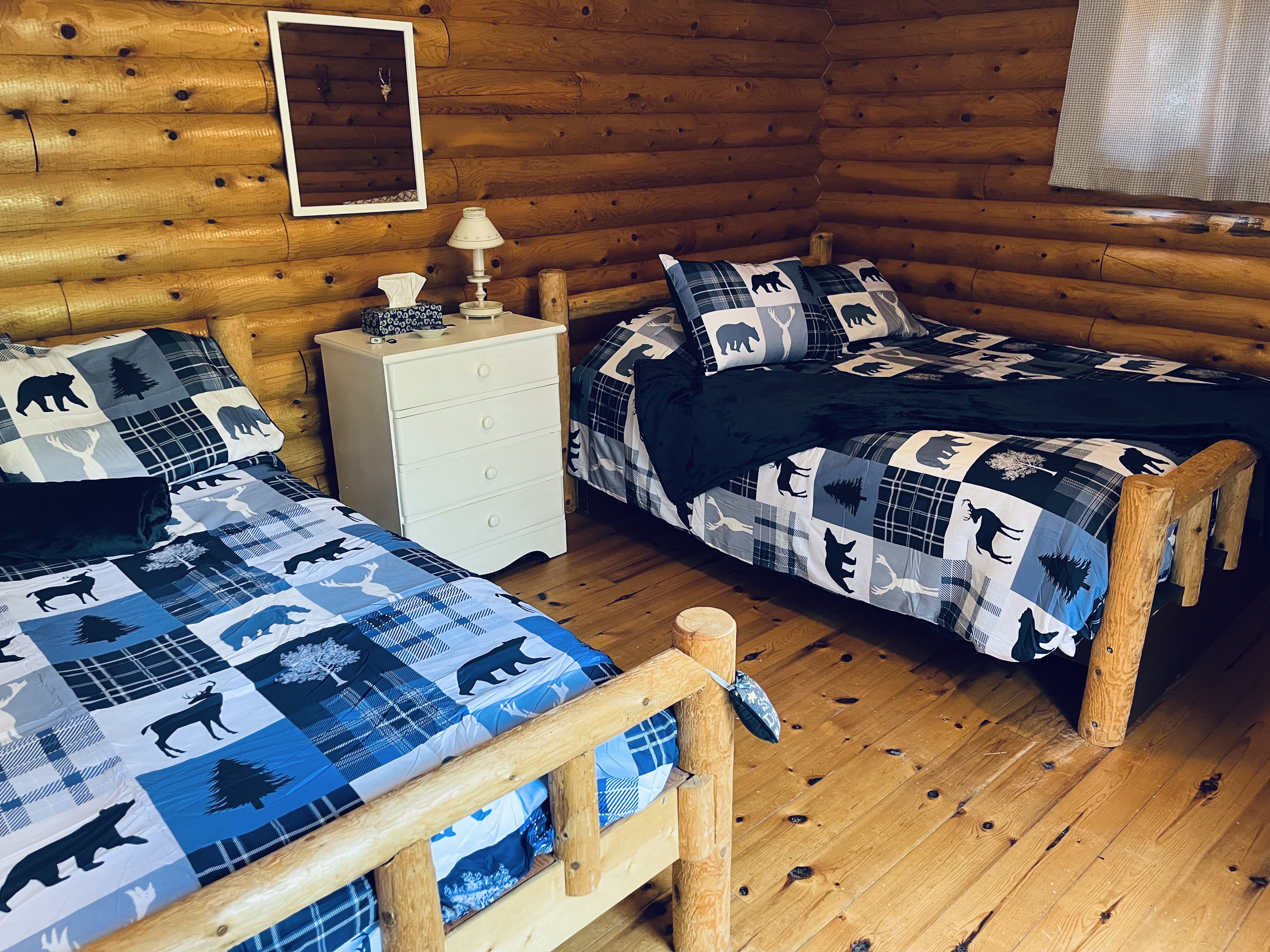 Rustic log cabin bedroom with matching handcrafted log beds and wilderness bedding