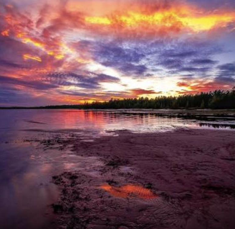 Vibrant sunset over the shallow waters and shoreline at Singing Sands Beach