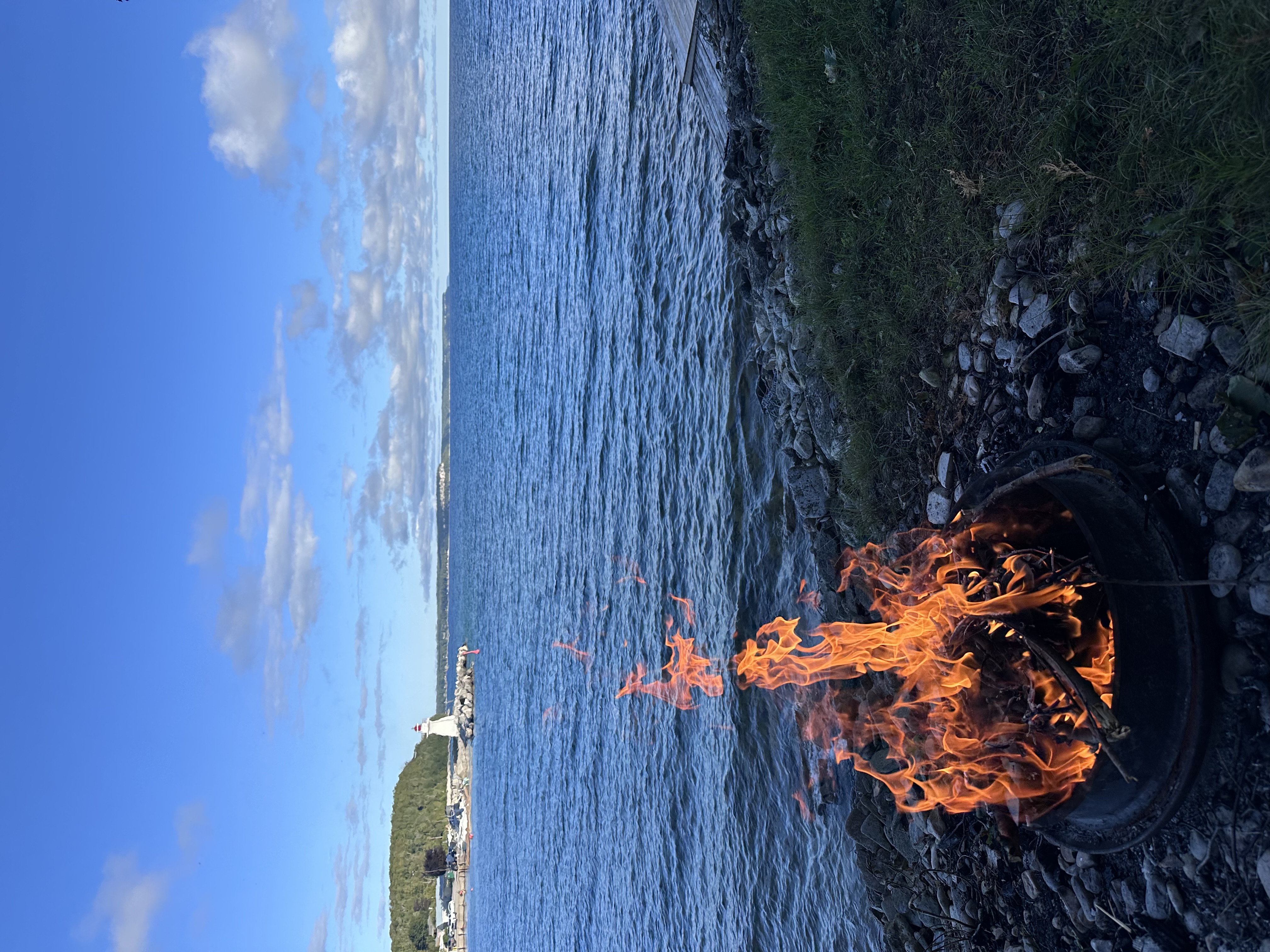 Evening fire pit on the rocky shore with Lion's Head lighthouse across the bay