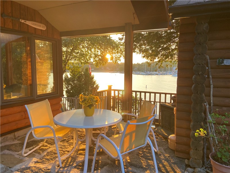 Stone patio deck with outdoor dining table overlooking Lion's Head harbour and marina at sunset
