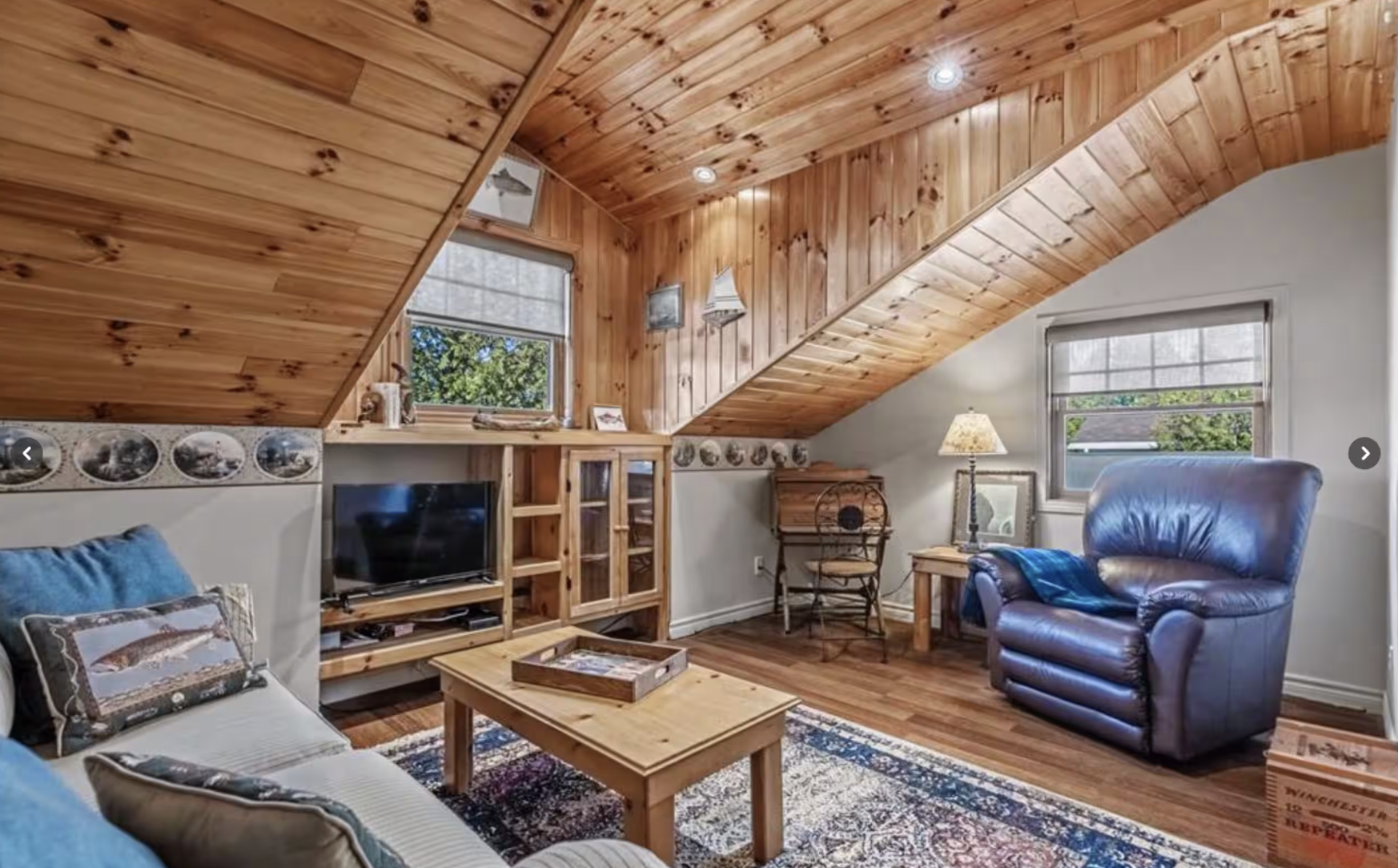 Cozy upper living lounge with leather recliner, sofa, books, and warm wood-paneled walls