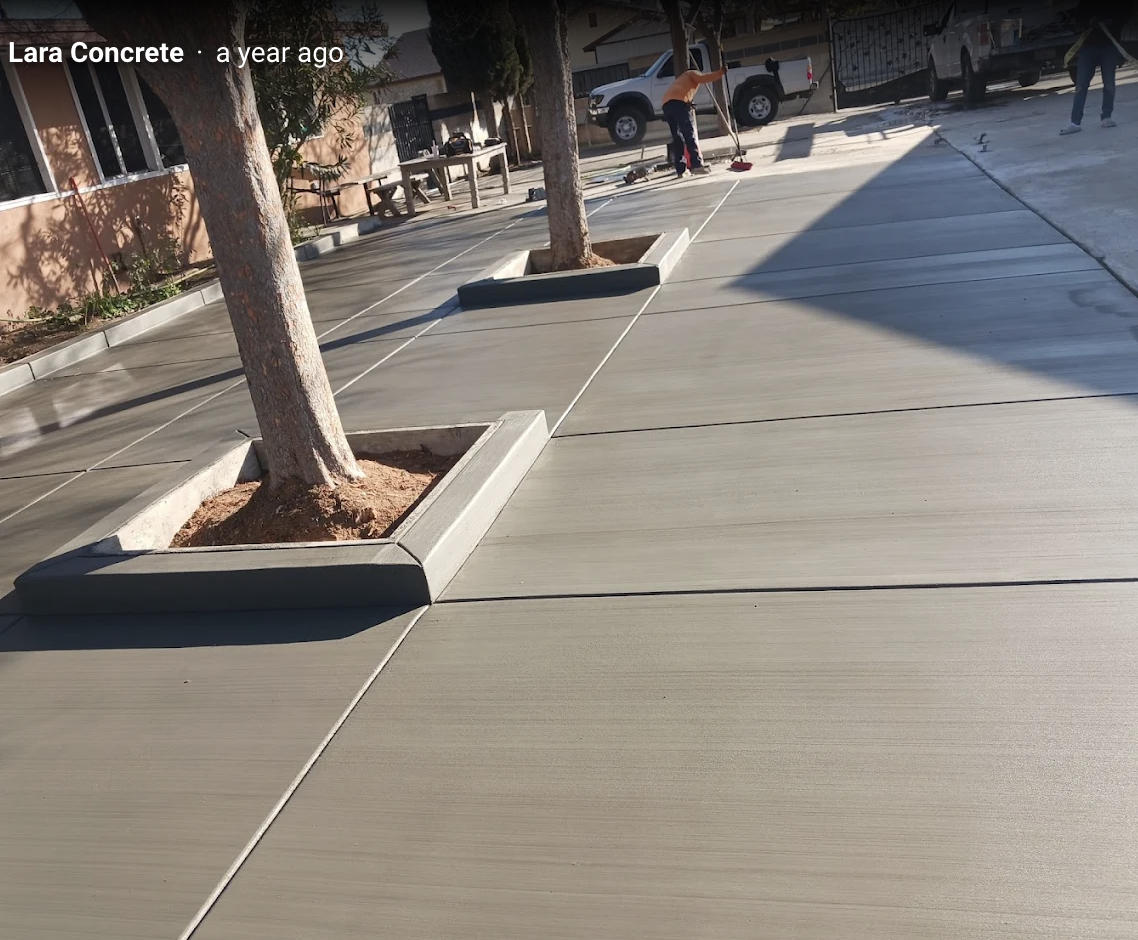 Large finished concrete driveway with clean broom finish and tree planters by LARA Concrete