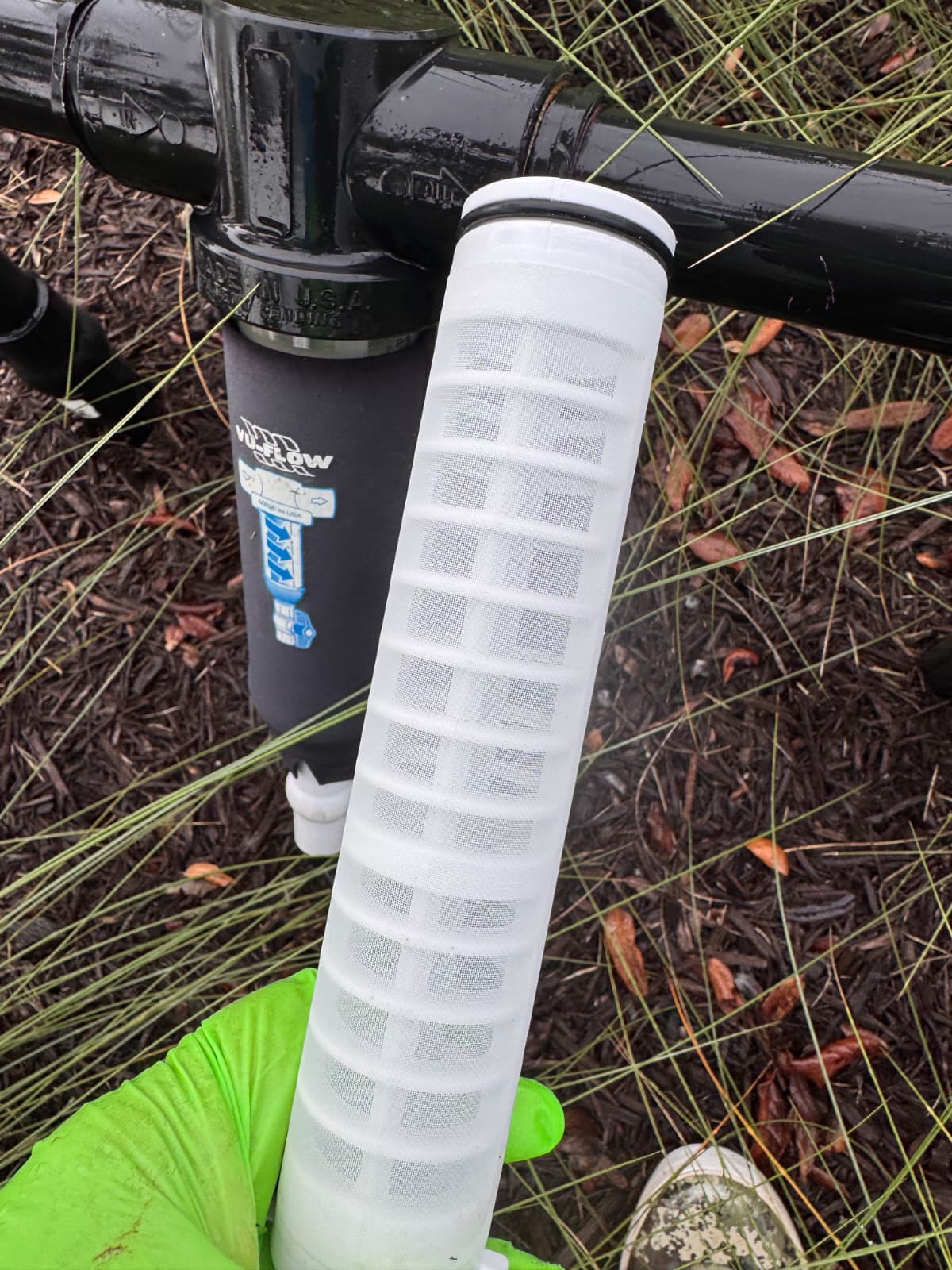 technician holding clean mesh screen element next to outdoor Vu-Flow filter housing