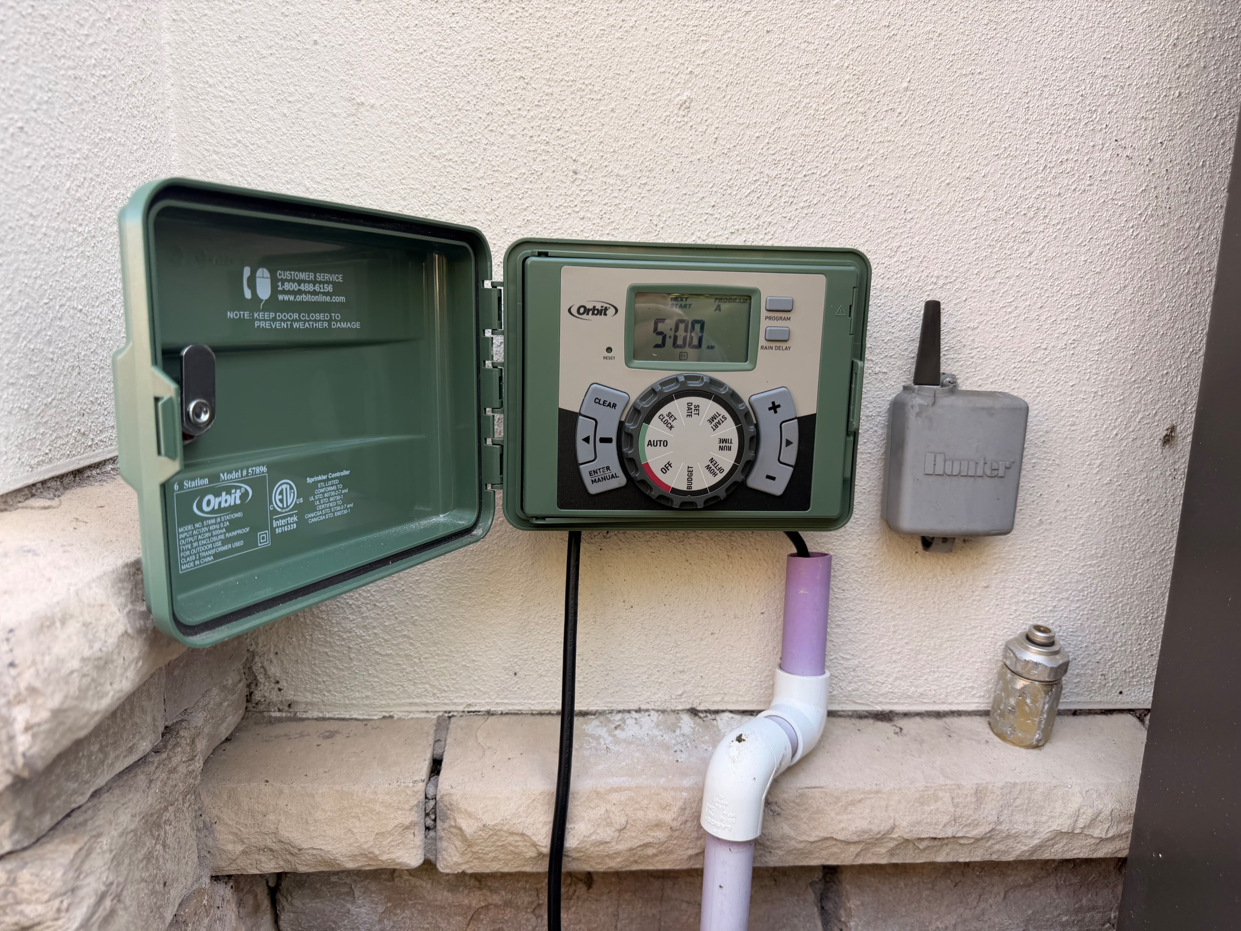 Orbit 6 station outdoor sprinkler timer with wireless Hunter rain sensor and reclaimed purple PVC conduit by Aenlle Home Service LLC