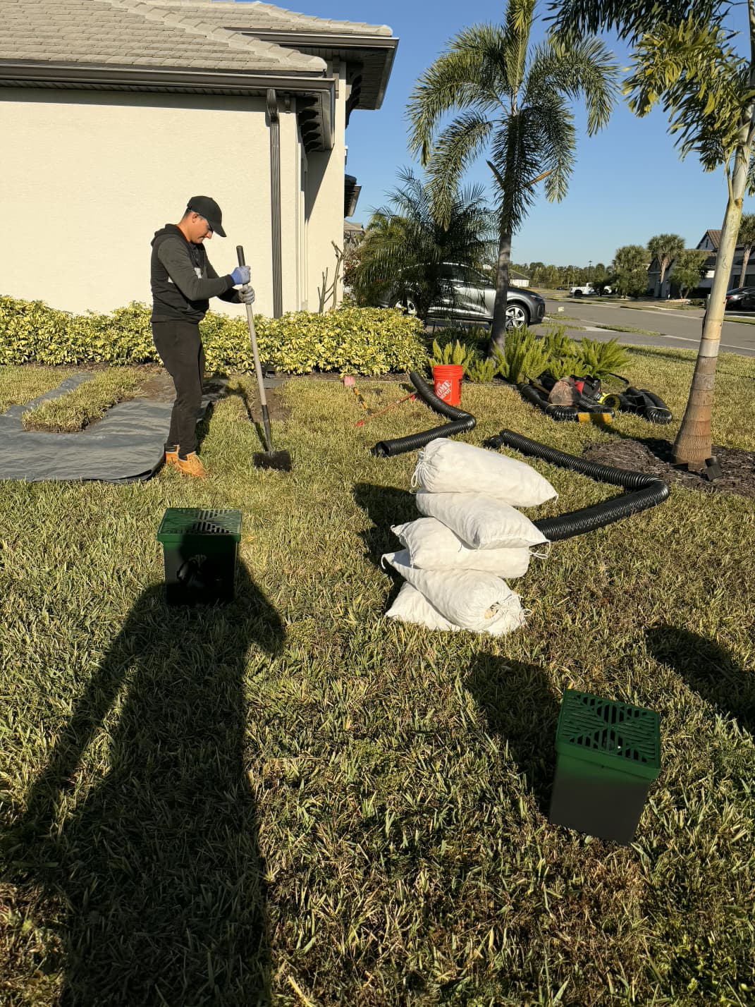 contractor trenching front lawn drainage system with catch basins and gravel in Sarasota FL