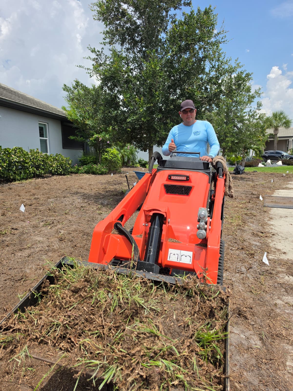 owner Angel Aenlle operating compact loader on lawn restoration project