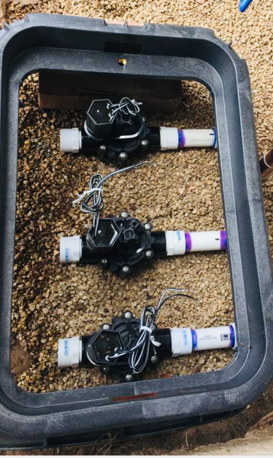 three-valve sprinkler solenoid manifold box with clean gravel bedding installed in Bradenton FL