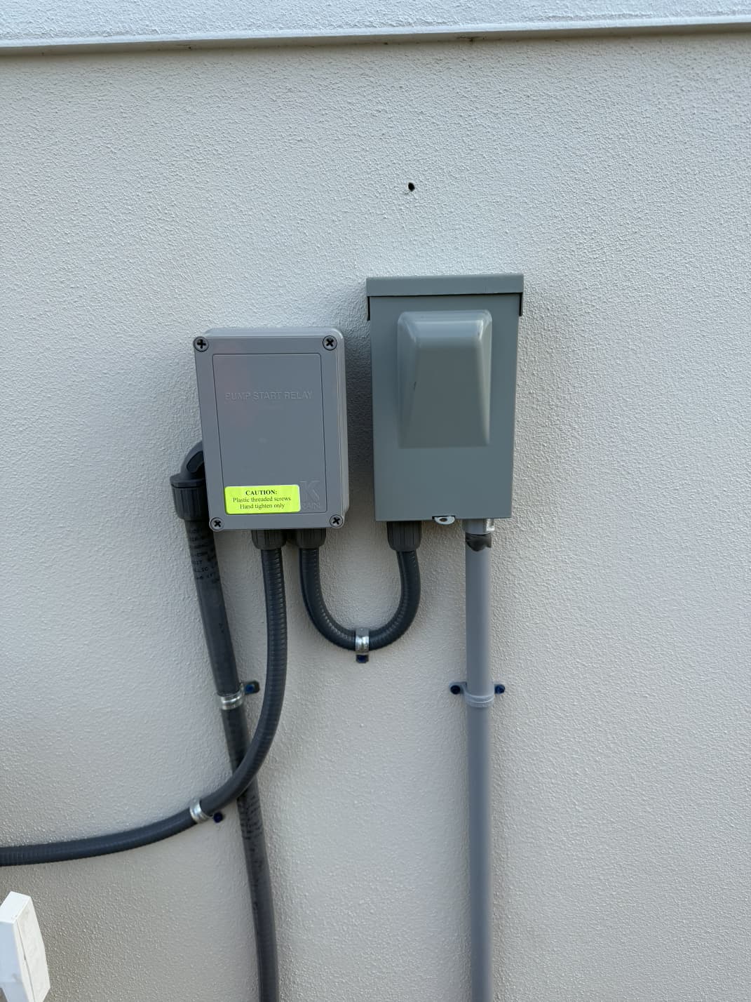 K-Rain pump start relay and electrical disconnect box mounted on exterior wall by Aenlle Home Service LLC