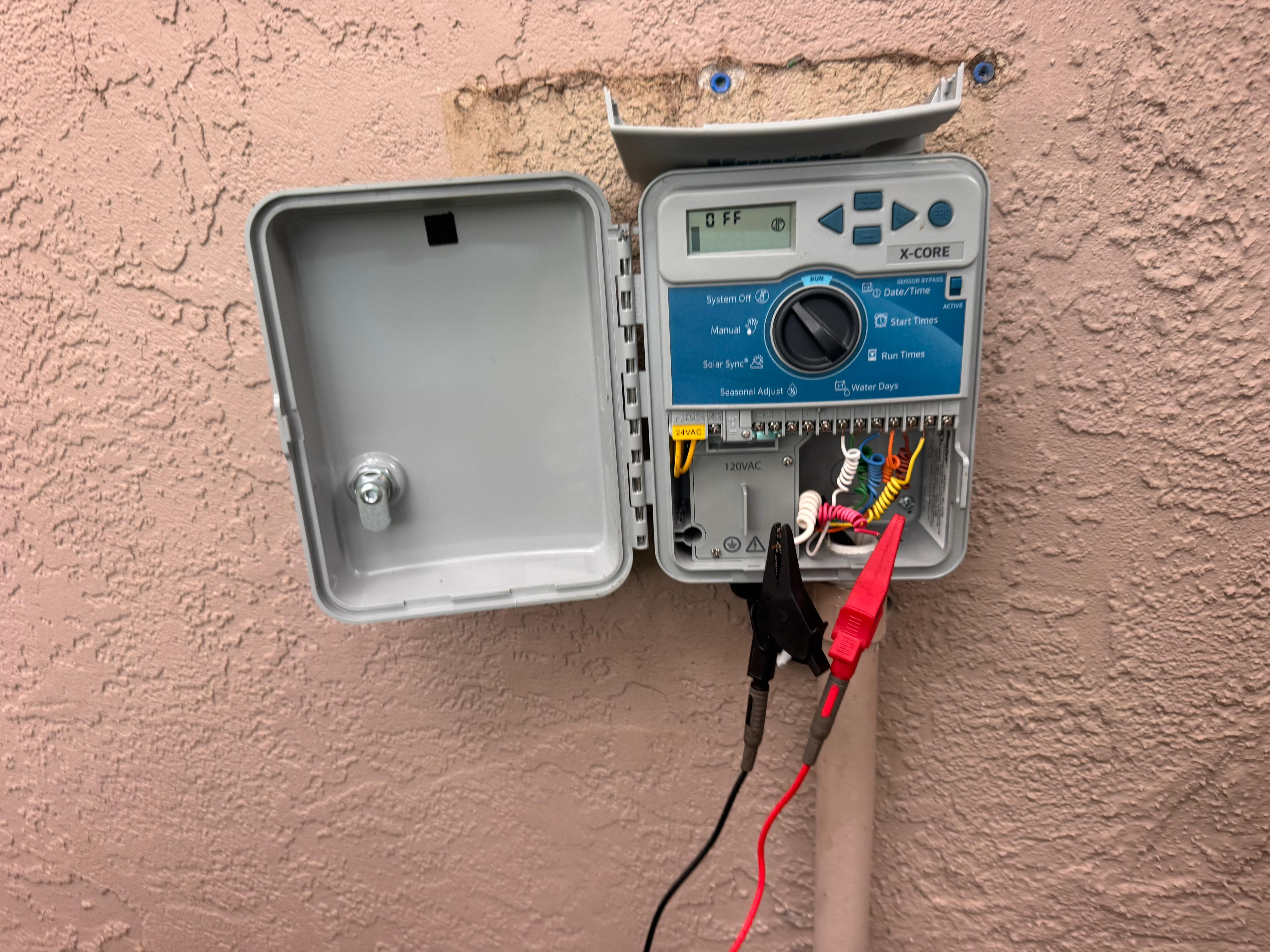 electrical diagnostic testing on outdoor Hunter X-Core sprinkler timer with alligator test leads