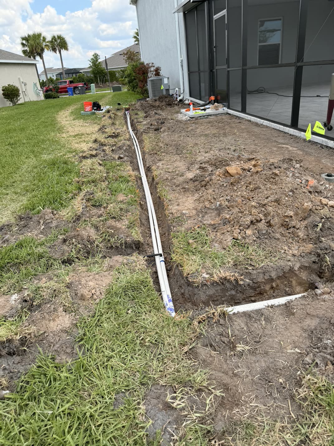 irrigation trenching and dual PVC sprinkler pipe installation alongside residential pool cage in Florida
