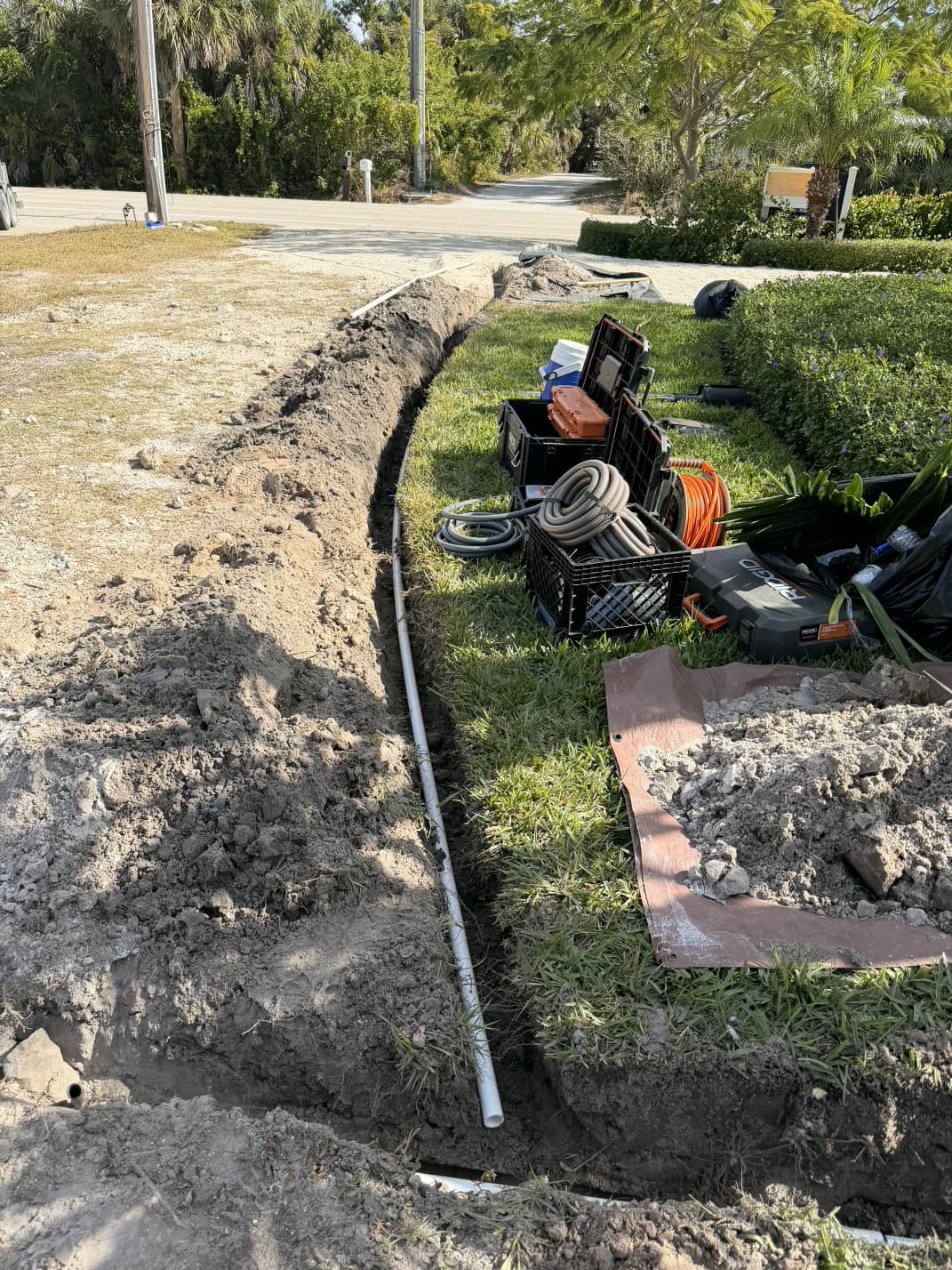 precision lawn irrigation trenching and PVC water mainline pipe run along driveway turf in Florida