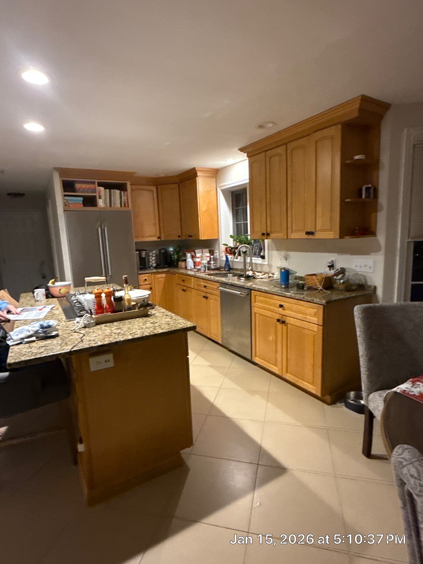 Before remodel: dated honey oak cabinets, busy brown granite counters, and tile flooring