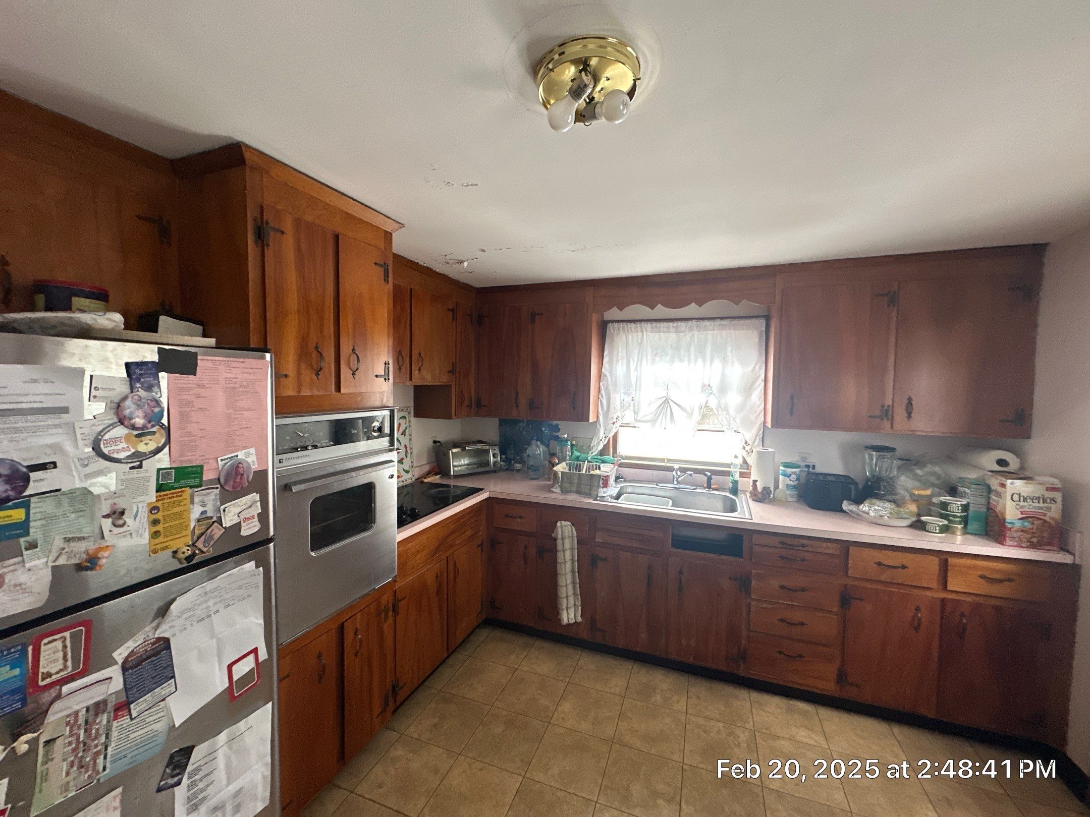 Before remodel: vintage dark wood cabinets, pink laminate countertops, and peeling ceiling