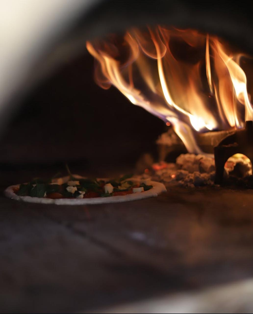 Pizza horneándose en el horno de leña a 485°C