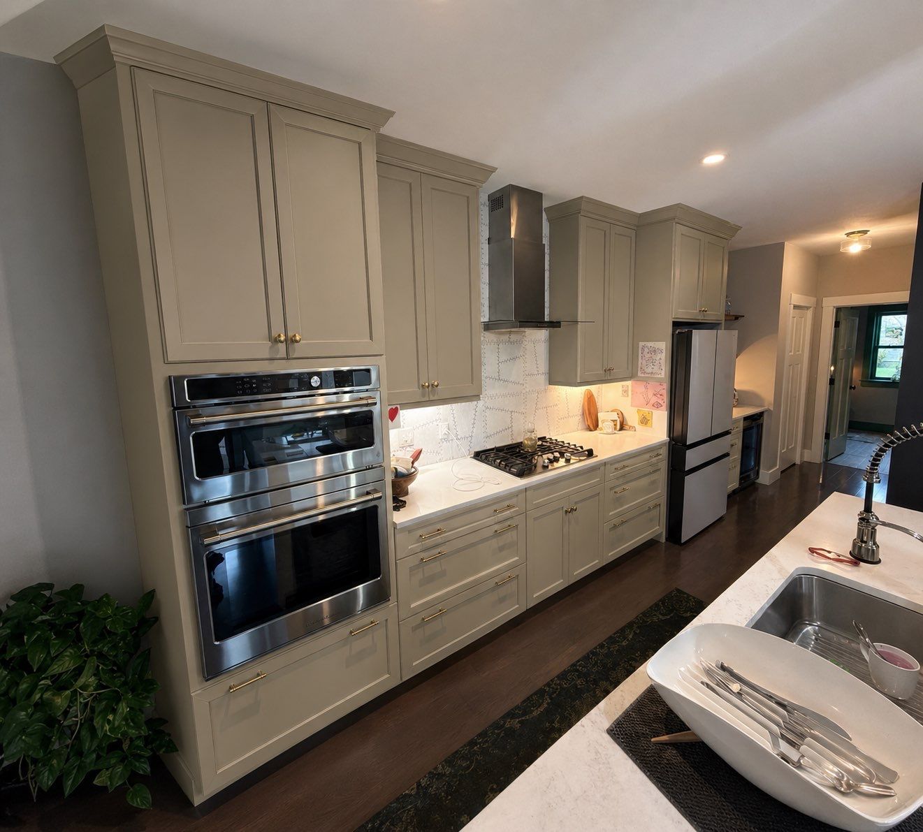 After cabinet painting: factory-smooth warm sage green painted kitchen cabinets with brushed gold hardware and double wall oven
