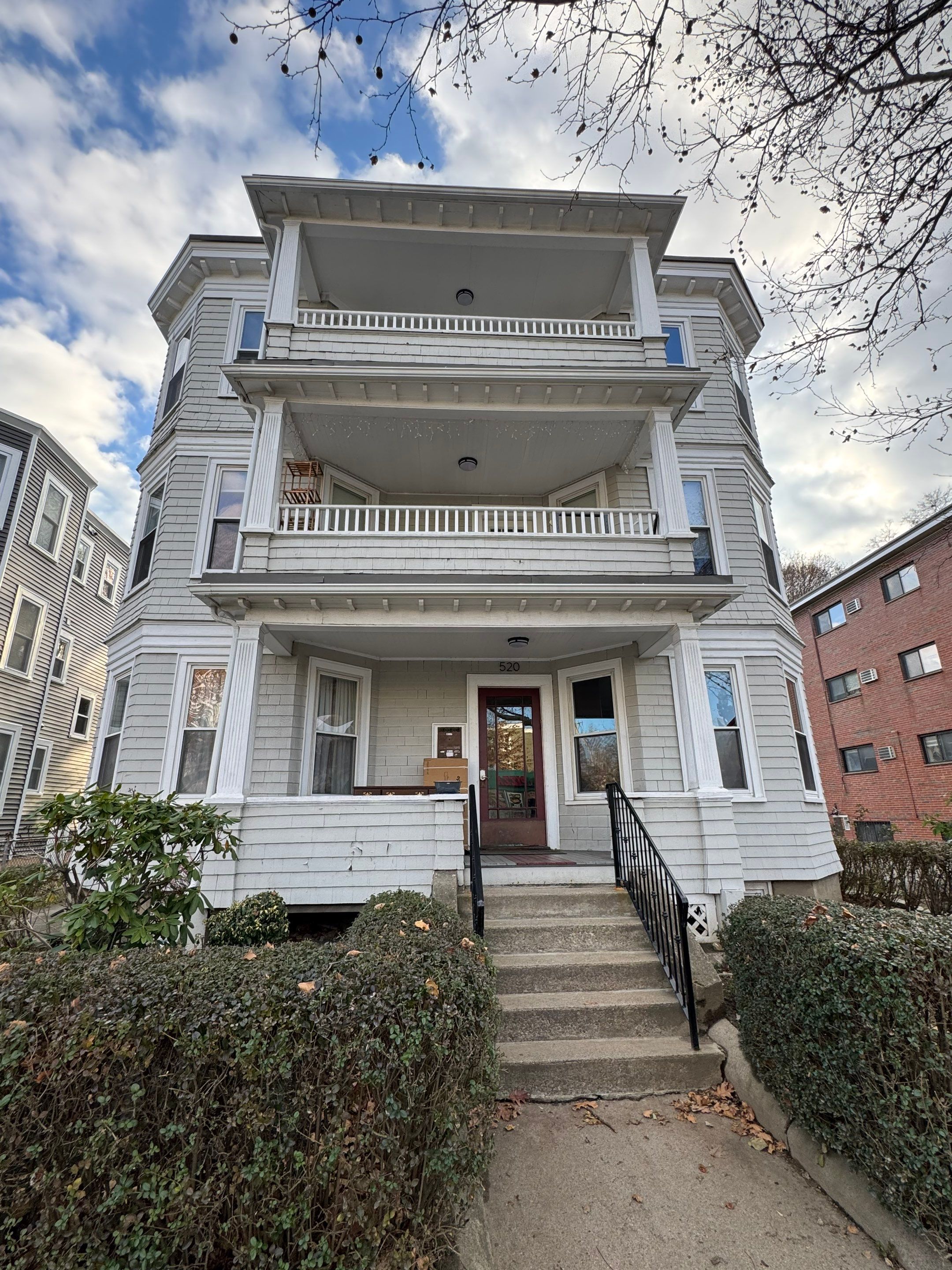 Before painting: faded, weathered grey shake siding on three-story multi-family building with dull trim