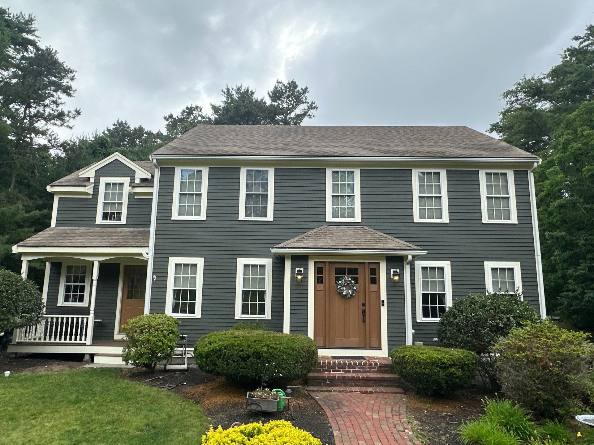 After painting: freshly painted Massachusetts colonial in modern deep charcoal grey with crisp white window casing and porch trim