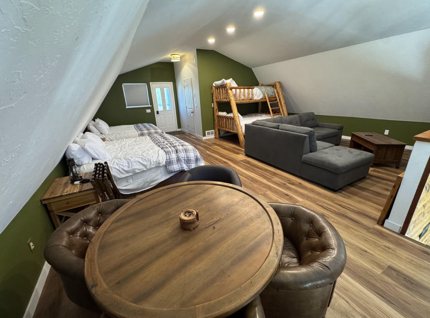 Spacious loft living room with circular table, sectional couch, and beds