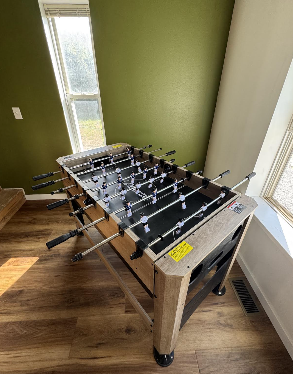 Upstairs foosball game table beside sunny windows