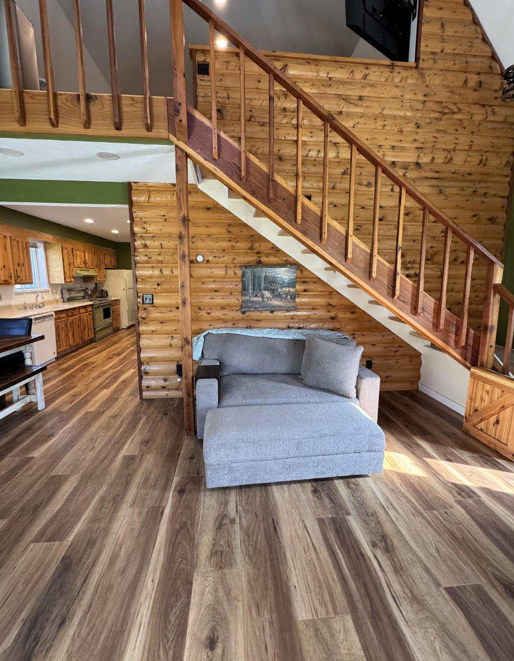 Warm log siding, open floor plan, and stairway to loft inside Borah Bunkhouse