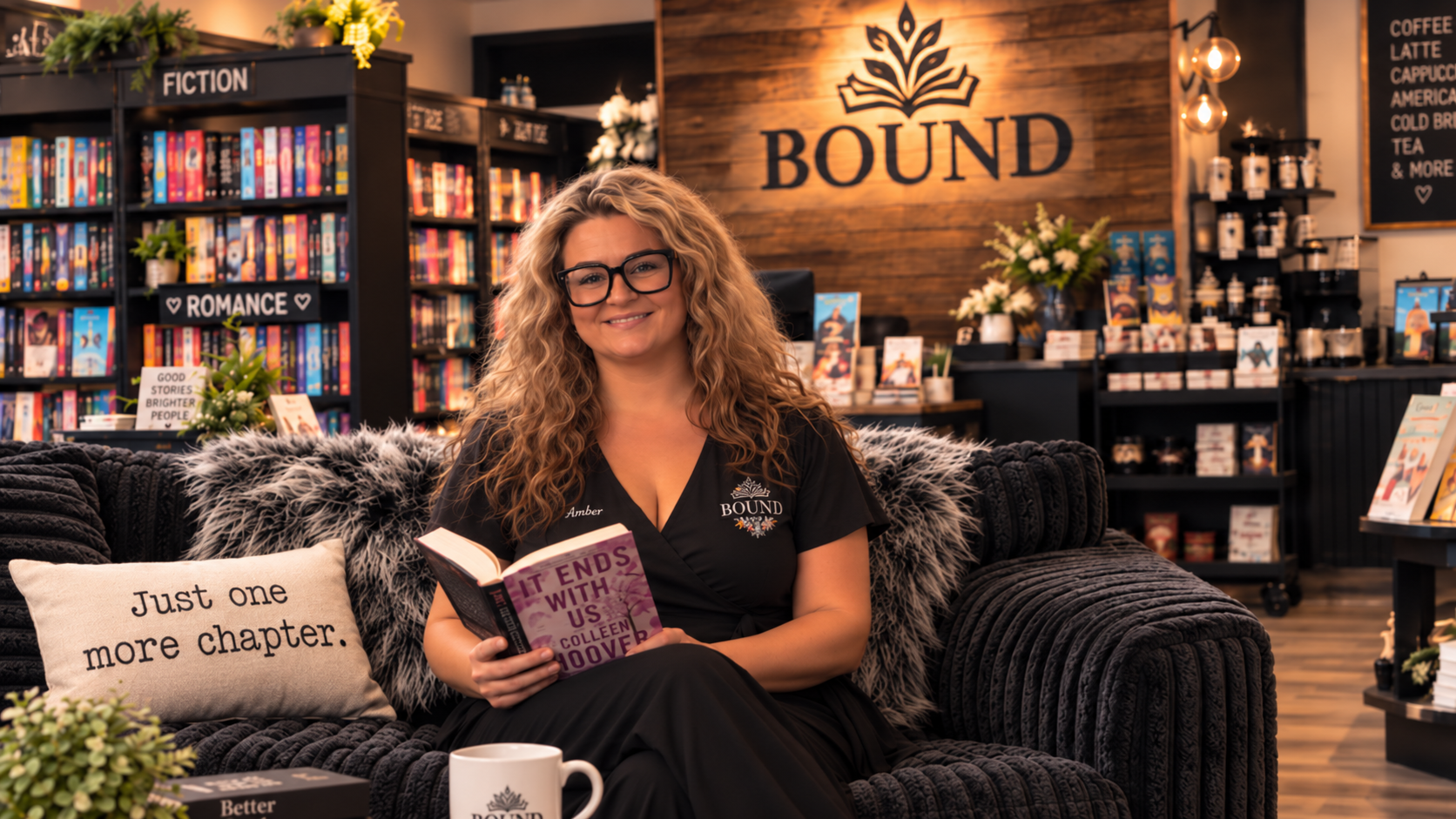 Amber, owner of Bound Lincolnton, reading a book on the cozy corduroy couch with the Bound logo wall in the background