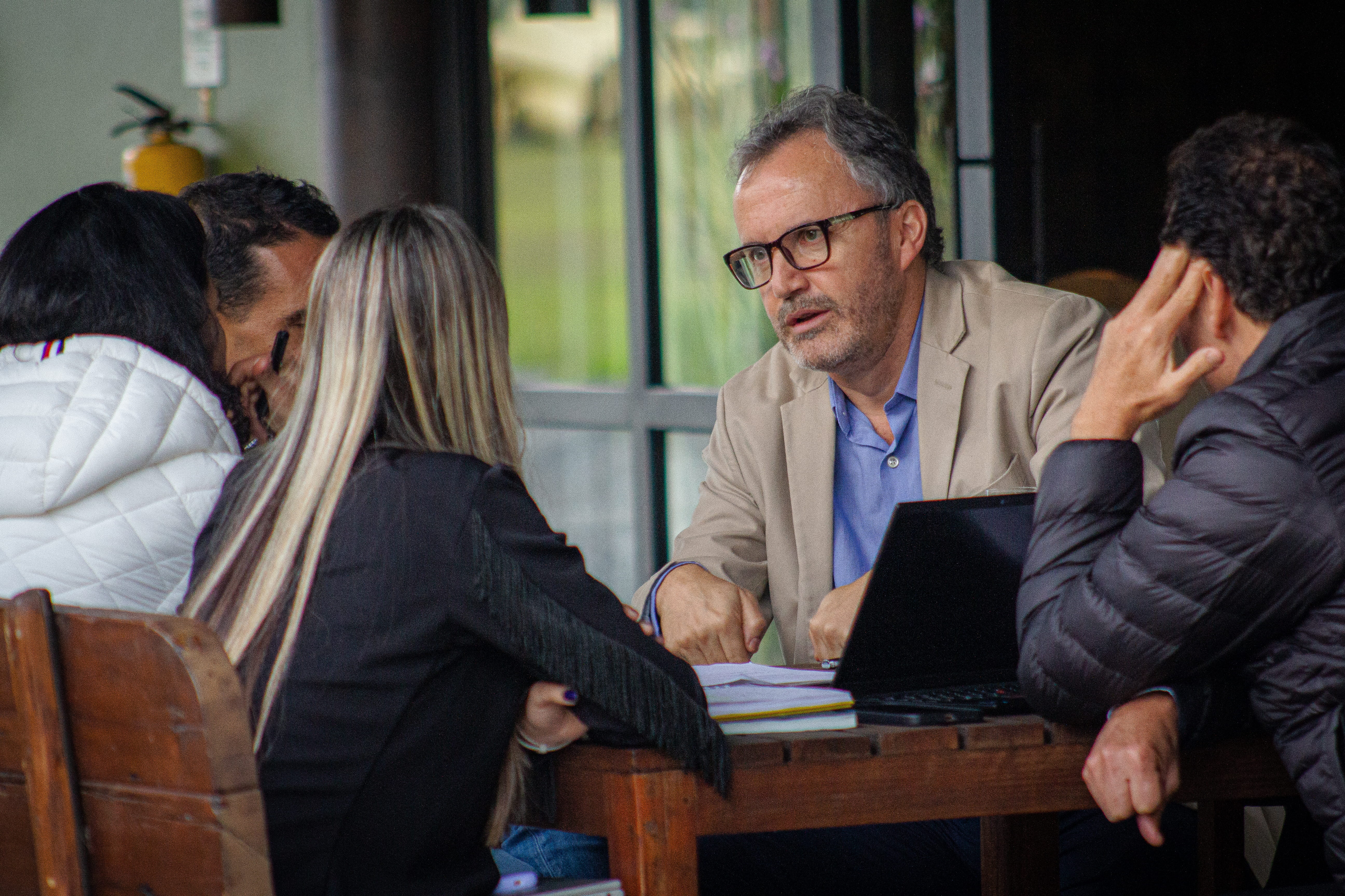 Facilitador guiando trabajo estratégico en mesa con equipo ejecutivo