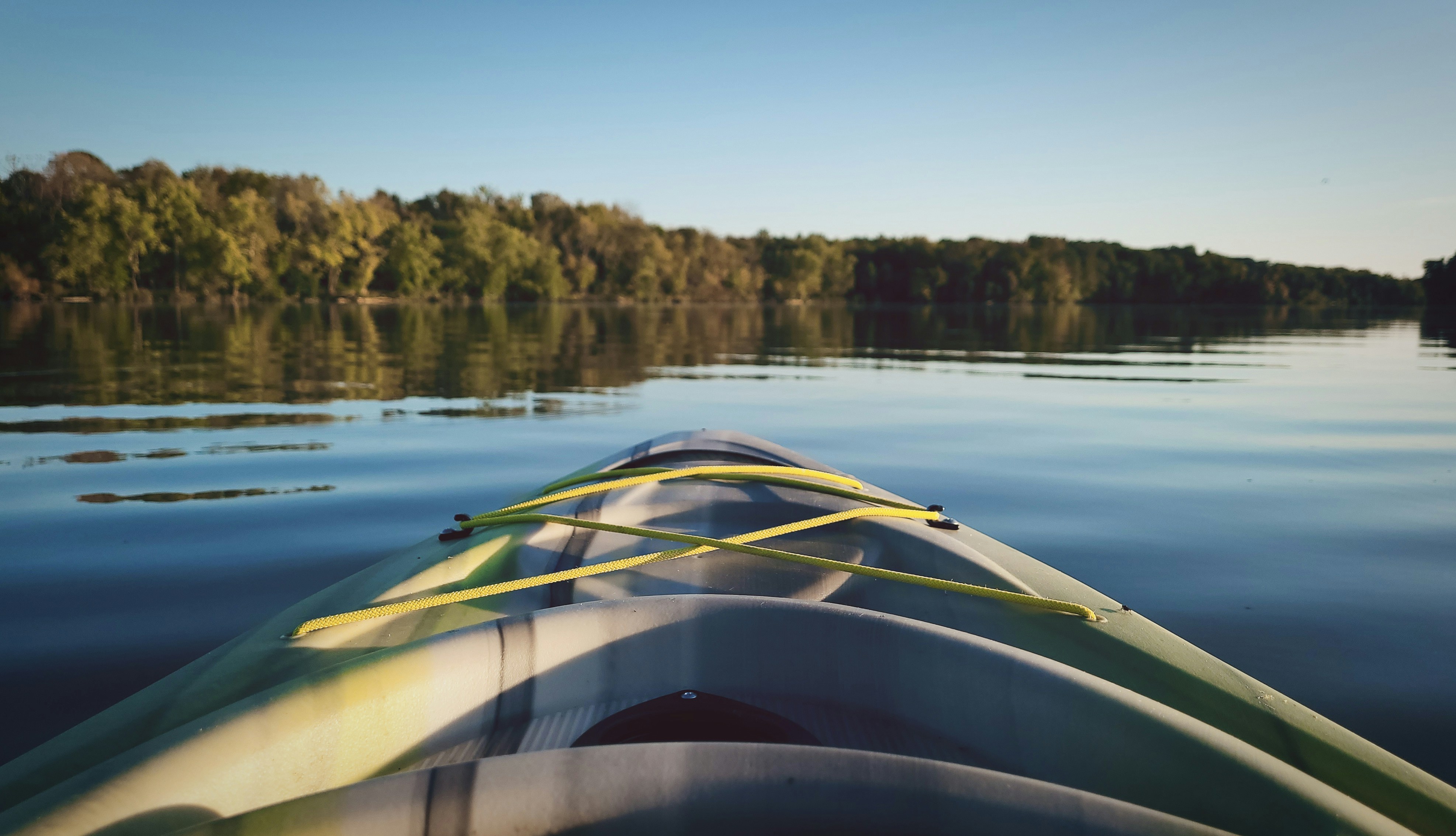 Calm West Michigan river with a kayak near a grassy launch for a late-summer kayaking guide.