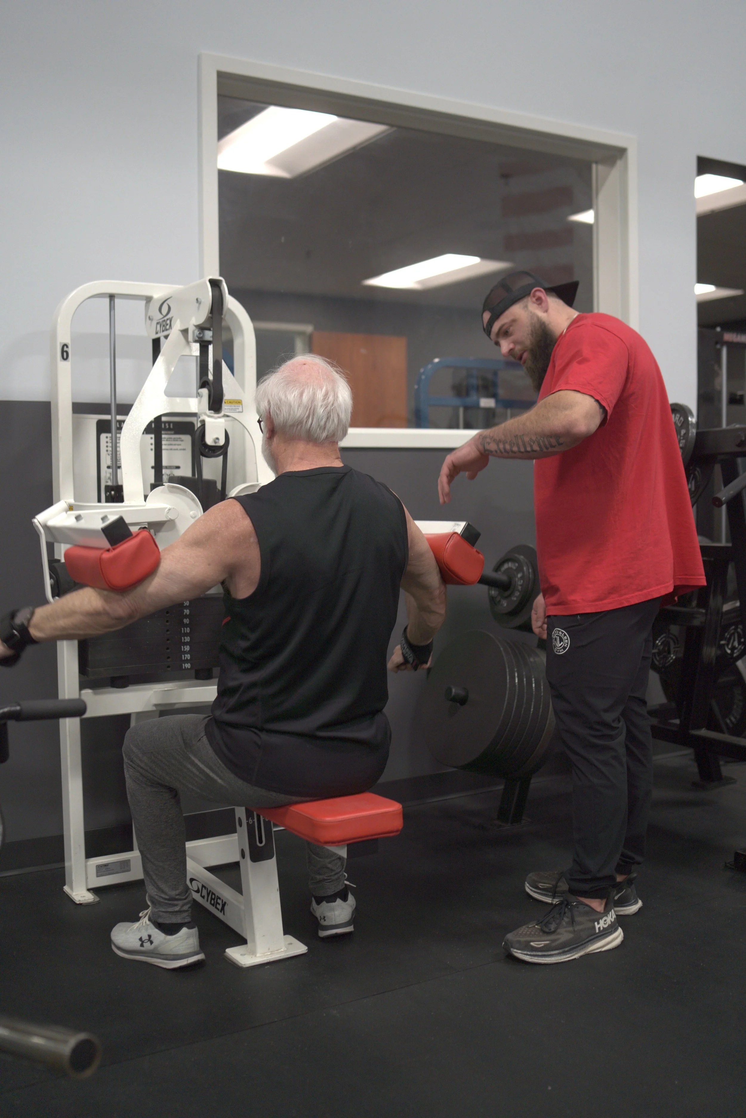JACKEDNLEEN coach instructing athlete on gym equipment