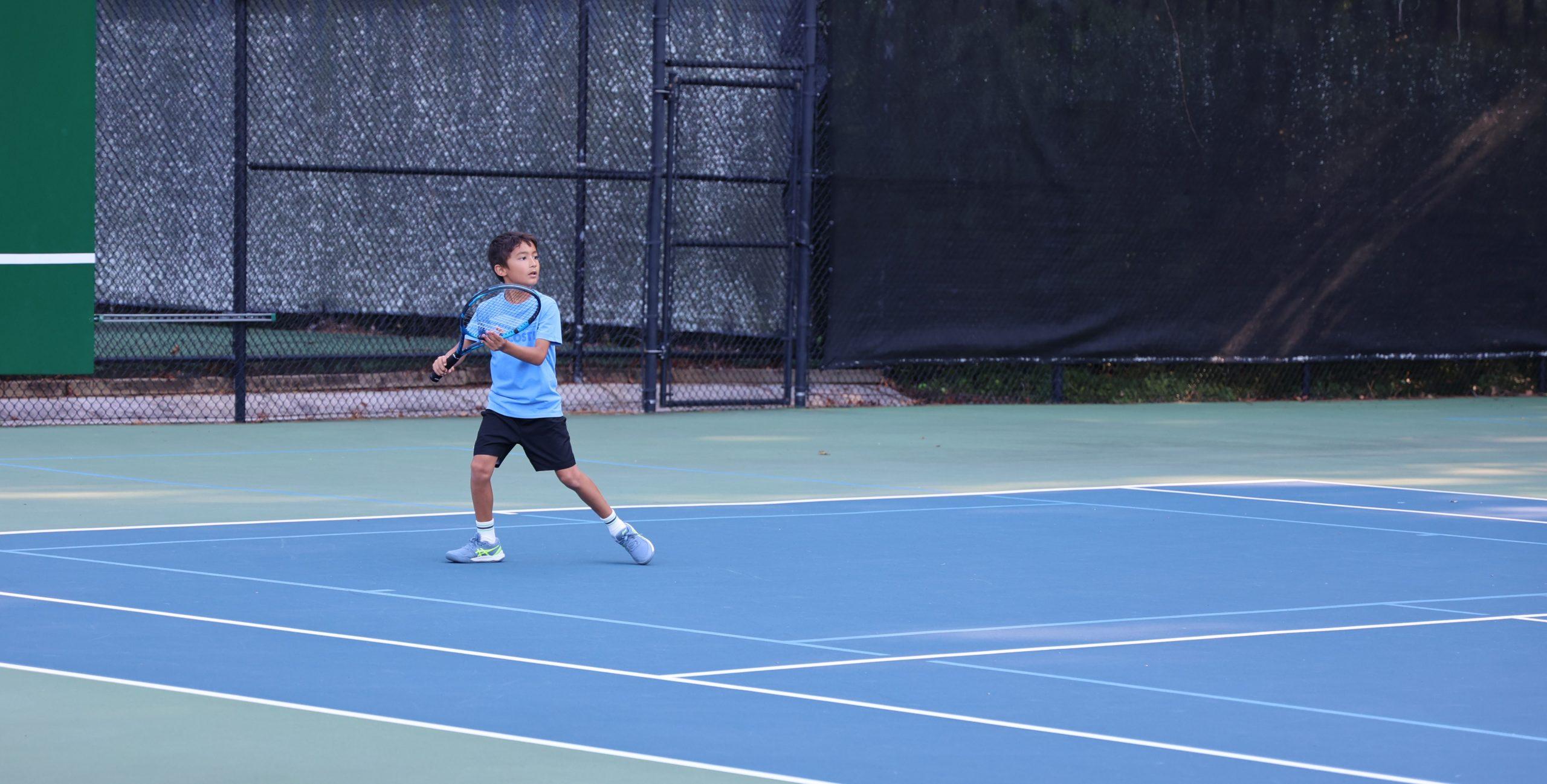 Junior tournament match on outdoor blue hard courts
